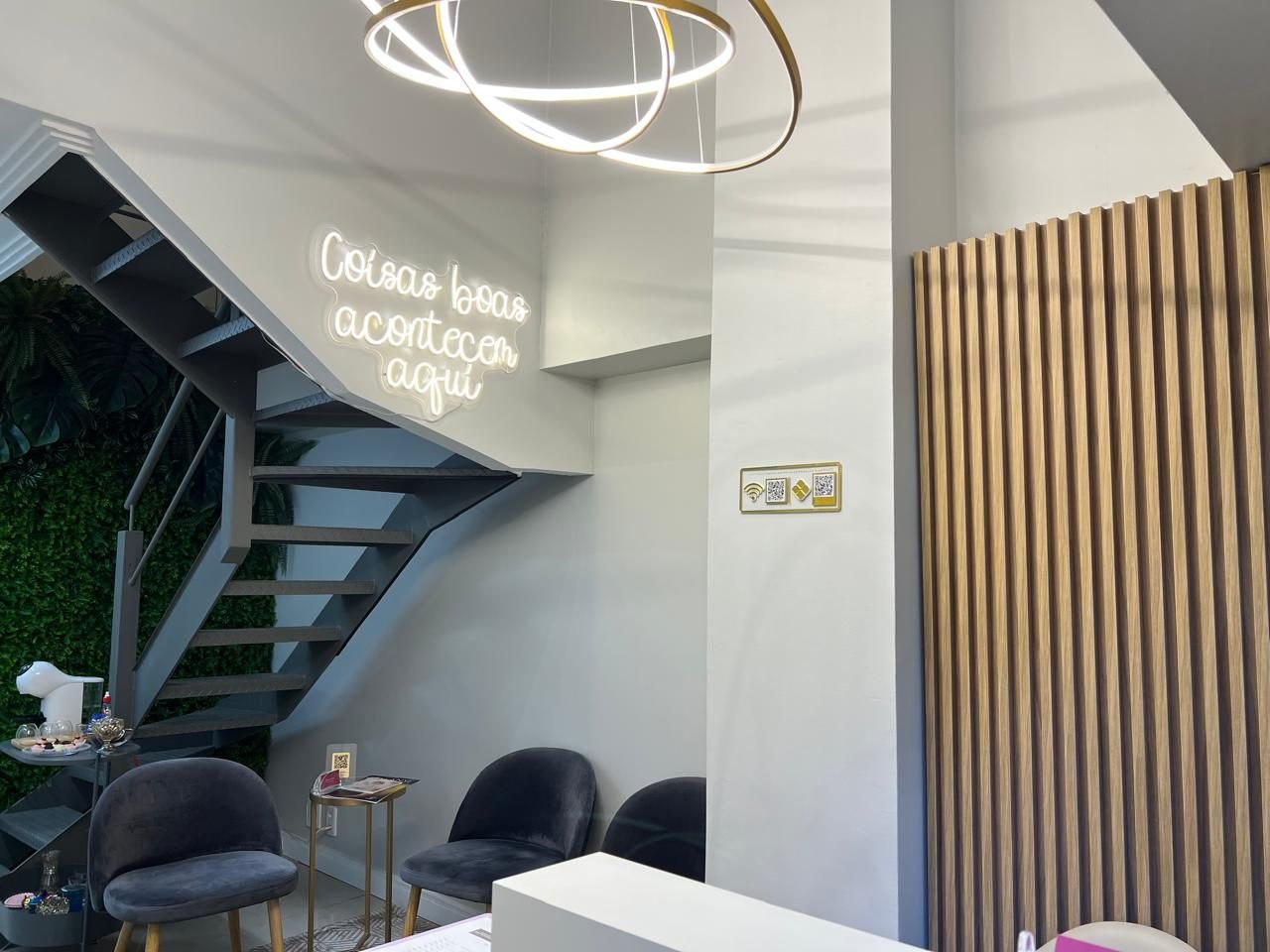 Recepção da Benquer com o neon 'Coisas boas acontecem aqui', a escada e o jardim vertical