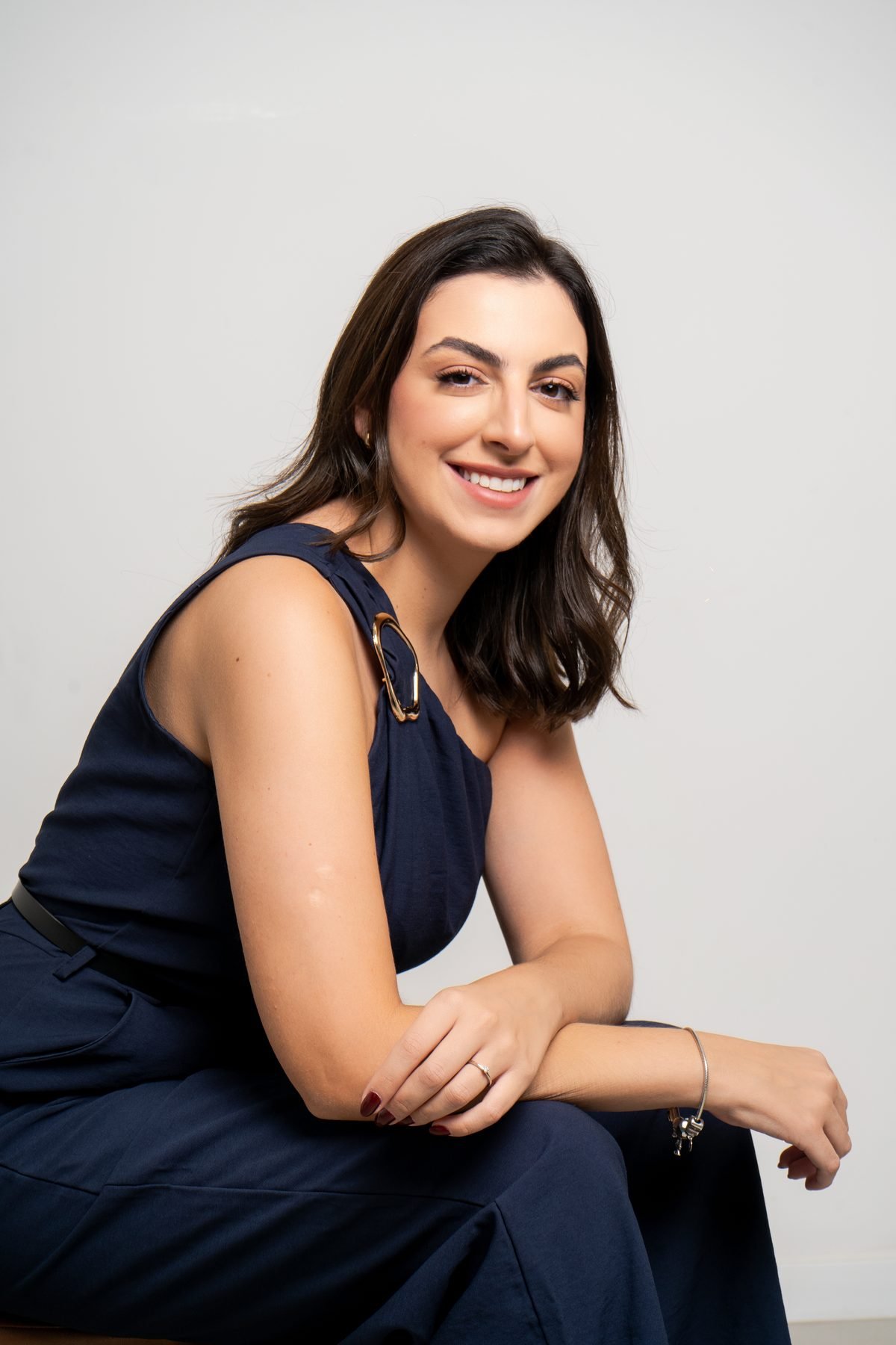 Dra. Gabrielle sentada, apoiada no joelho, sorrindo