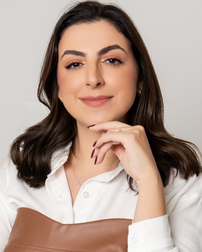 Retrato da Dra. Gabrielle de camisa branca, com a mão no queixo