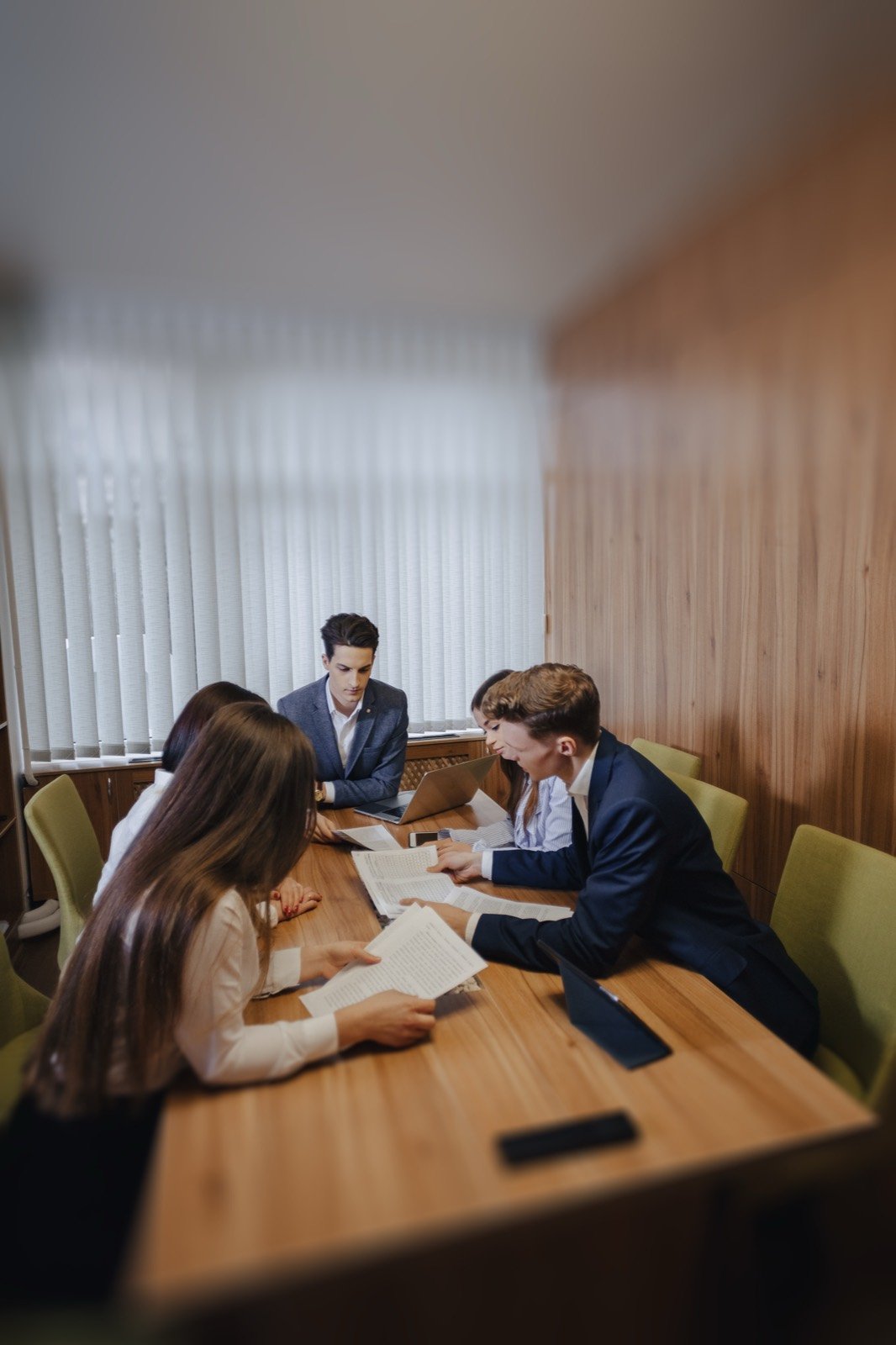 Equipe de advogados reunida em volta de uma mesa de madeira, lendo documentos.