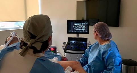 Equipe acompanhando o ultrassom Doppler durante um procedimento