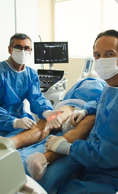 Dr. Marcelo Zanoni em procedimento com laser ao lado de um colega